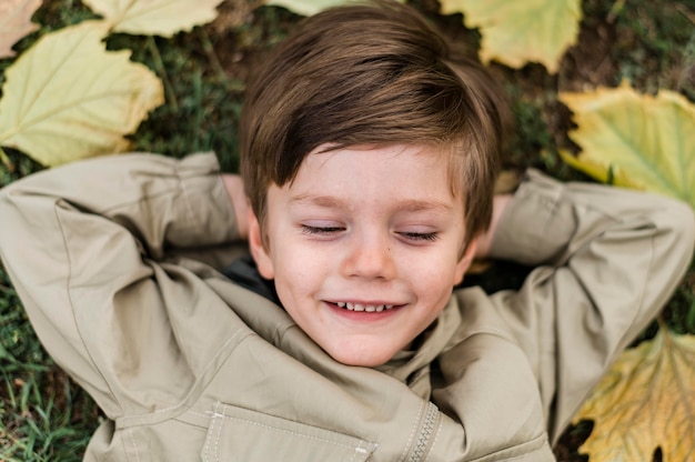 Top view smiley little boy staying on the grass