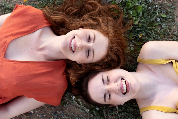 Free photo top view smiley women laying on grass