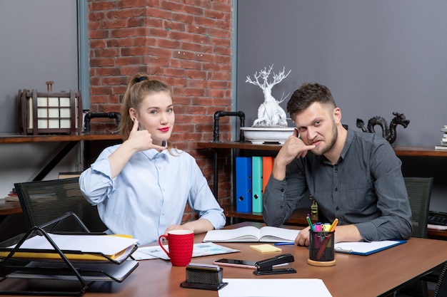 Top view of smiling and motivated skilled workers making call me gesture in the office