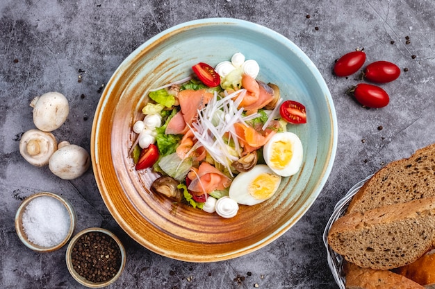 Top view of smoked salmon salad with boiled egg tomato lettuce mushroom onion