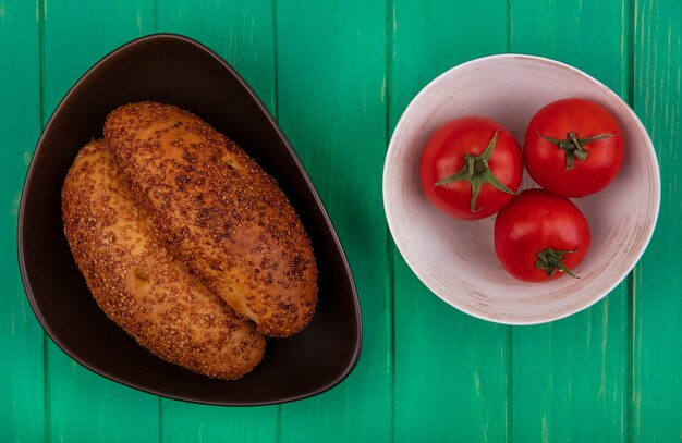 Top view of soft and delicious sesame patties on a brown bowl with fresh tomatoes on a bowl on a green wooden background