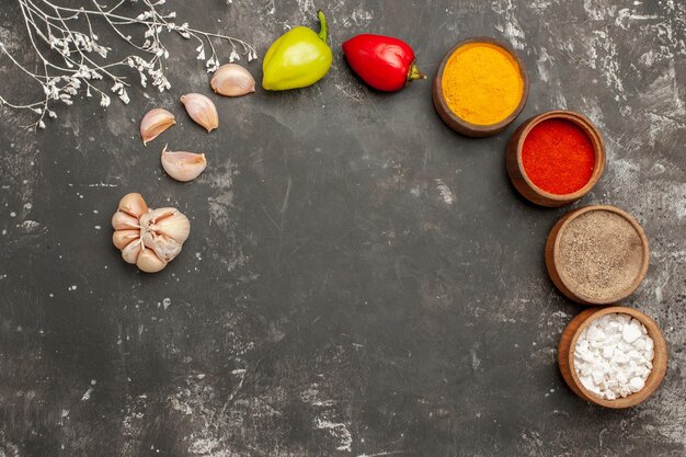 Top view spices on the table colorful spices in bowl garlic ball pepper on the dark table