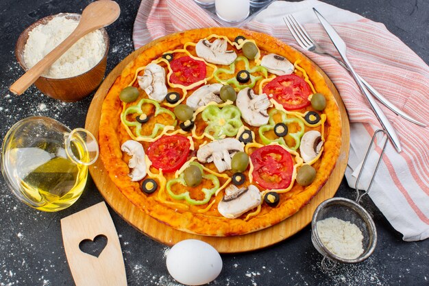 Top view spicy mushroom pizza with red tomatoes bell peppers olives all sliced inside with oil on the dark background pizza dough