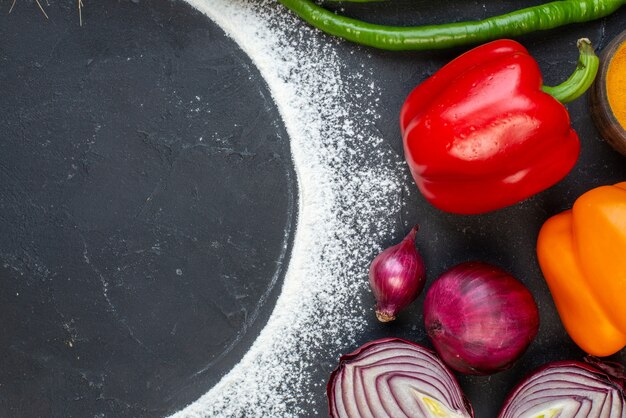 Top view sprinkled flour circle green and red peppers red onions on table free space