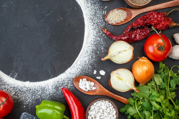 Top view sprinkled flour circle tomatoes onions rice in wooden spoon coriander on table free space