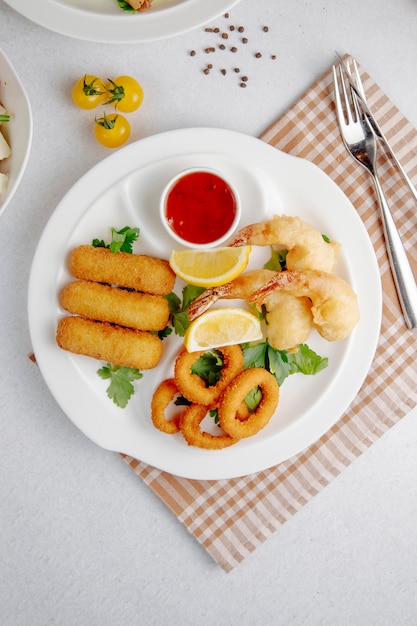 Top view of squid and shrimp tempura and fried cheese stick on a white plate