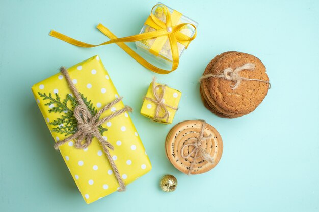 Top view of stacked various delicious cookies yellow gift boxes on pastel green background