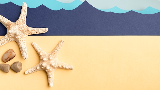 Free photo top view of starfish and rocks with paper ocean