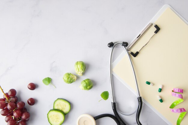 Top view stethoscope with cucumber slices and grapes