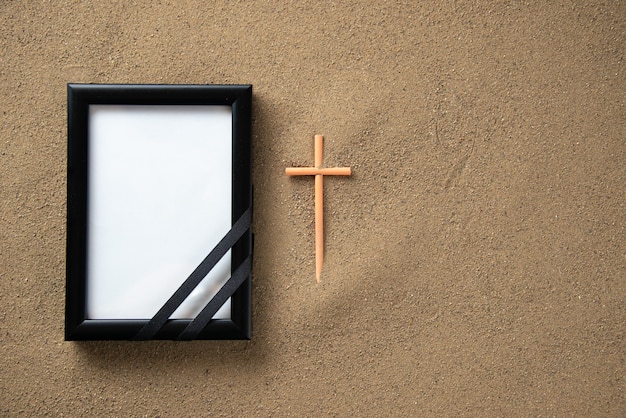 Top view of stick cross with picture frame on the sand 