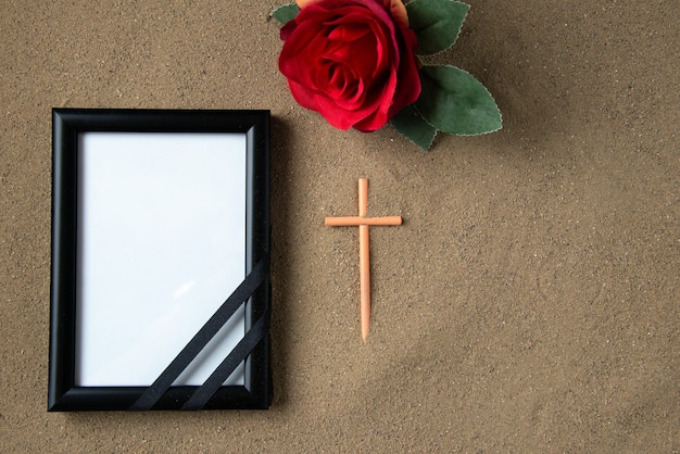 Top view of stick cross with red flower and picture frame on the sand death funeral palestine