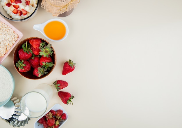 Top view of strawberries in bowl with cottage cheese butter milk oats on left side and white with copy space