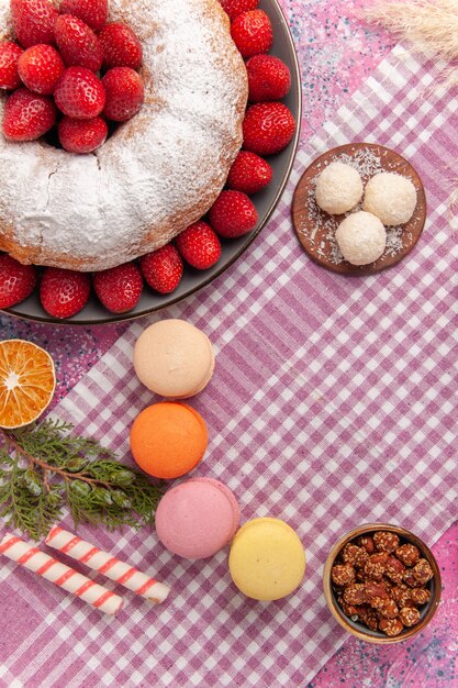 Top view sugar powdered pie strawberry cake with macarons on the pink