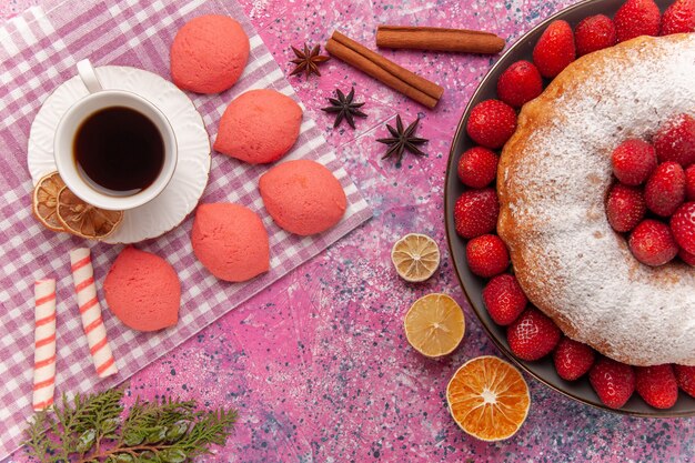 Top view sugar powdered pie strawberry cake with tea and cakes on pink