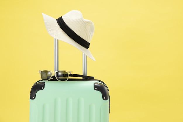 Free photo top view of a suitcase, sunglasses, camera and hat on a yellow background - vacation concept