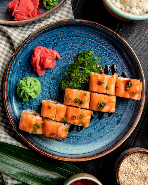 Free photo top view of sushi rolls with salmon eel avocado and cream cheese on a plate with ginger and wasabi