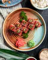 Free photo top view of sushi rolls with tuna on a plate with ginger and wasabi on wooden surface