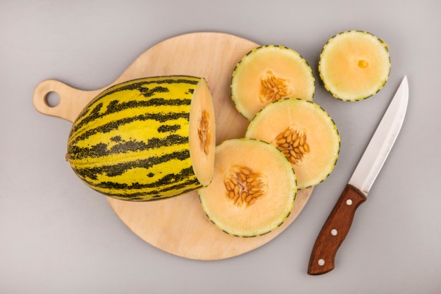 Free photo top view of sweet cantaloupe melon with slices on a wooden kitchen board with knife on a white wall