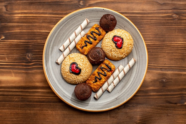 Free photo top view sweet cookies delicious sweets inside plate on brown rustic background tea cookie biscuit sugar sweet