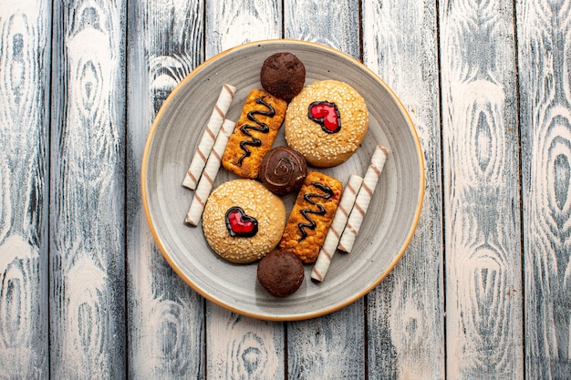 Top view sweet cookies delicious sweets inside plate on grey rustic background tea cookie biscuit sugar sweet