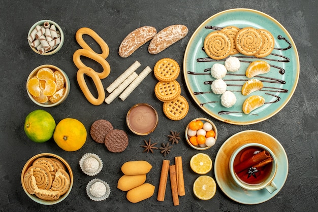 Top view sweet cookies with biscuits and tea on grey background