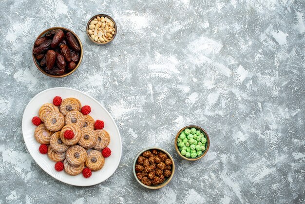 Top view sweet cookies with candies and confitures on white background cookie sugar biscuit cake tea sweet