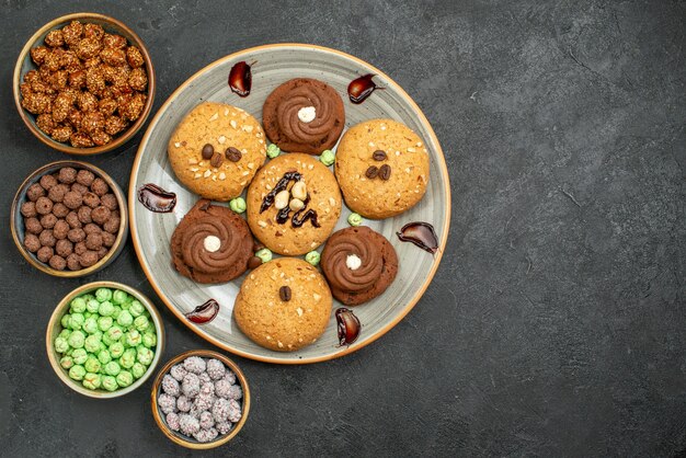 Top view sweet cookies with candies on grey desk sugar cookie sweet biscuit cake tea