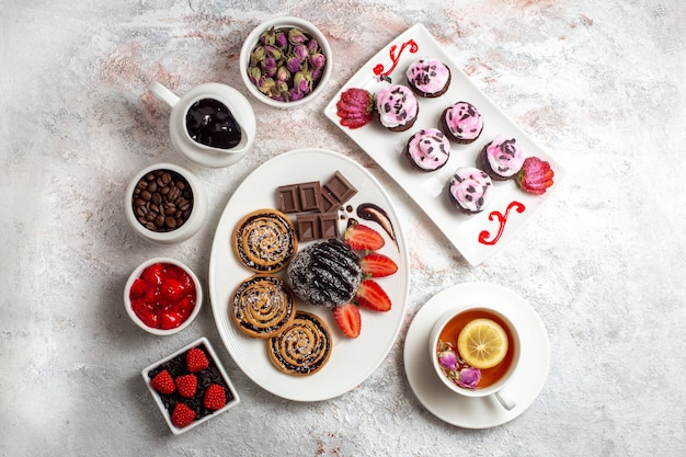 Free photo top view sweet cookies with chocolate cake and tea on the white background cookie biscuit sugar tea sweet cake