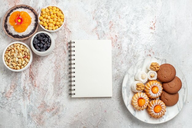 Top view of sweet cookies with nuts and dessert on white