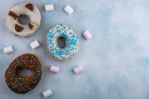 Top view sweet donuts with marshmallows on a gray table