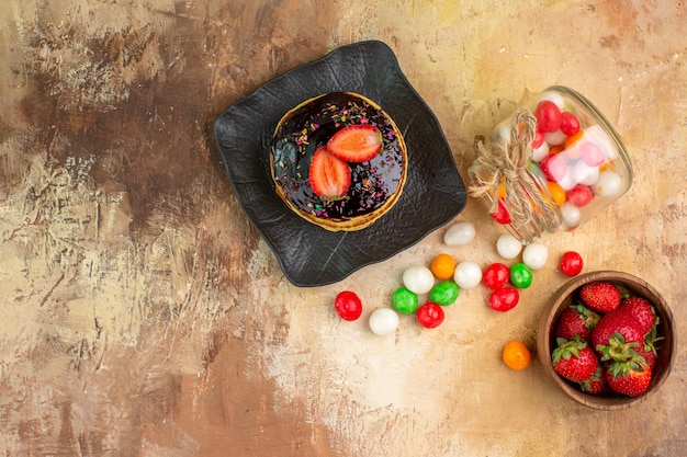 Top view sweet pancakes with colorful candies on wooden desk