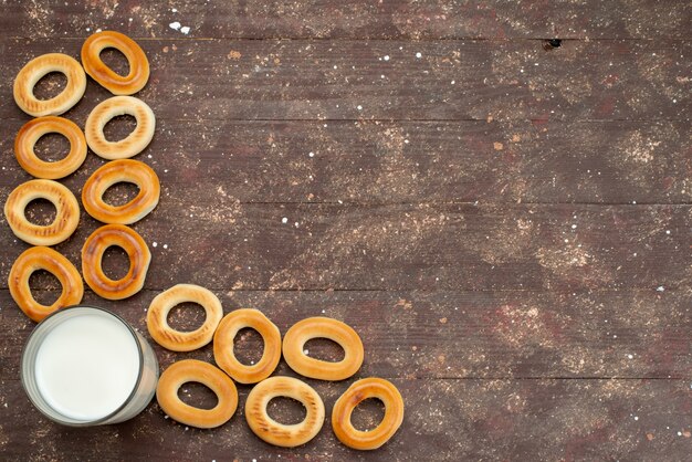 Top view sweet round crackers dry along with glass of cold milk on brown, cookie biscuit drink breakfast