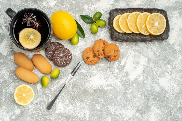 Top view sweets a cup of tea with lemon cookies citrus fruits sliced lemon fork