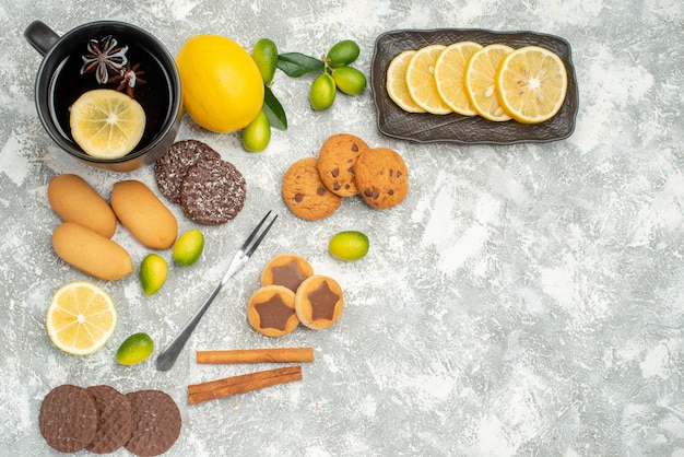 Top view sweets a cup of tea with star anise citrus fruits sliced lemon fork appetizing cookies