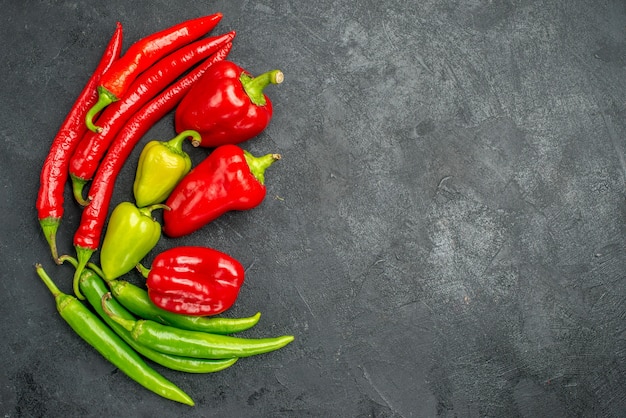 Top-view symmetric framed peppers with its bright colors on dark surface with free space