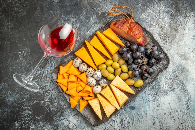 Top view of tasty best snack on a brown tray and fallen wine glass on ice background