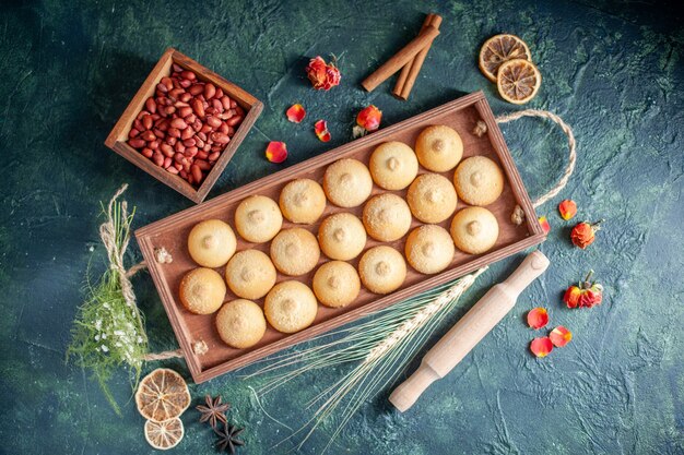 Top view tasty biscuits inside wooden box on dark background sugar cookie biscuit pie color sweet nut tea cakes