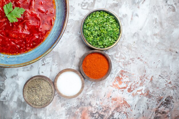 Top view of tasty borsch ukrainian beet soup with seasonings on white surface