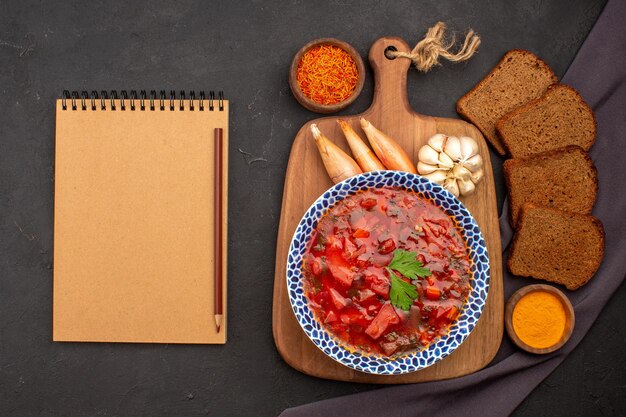 Top view tasty borsch ukranian beet soup with dark bread loafs on dark space