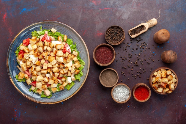 Top view tasty caesar salad with seasonings on the dark desk