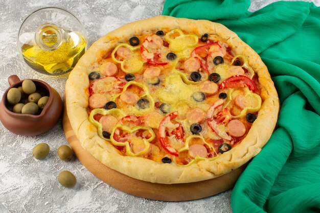 Top view tasty cheesy pizza with black olives sausages and red tomatoes along with oil on the grey desk fast-food italian dough meal bake