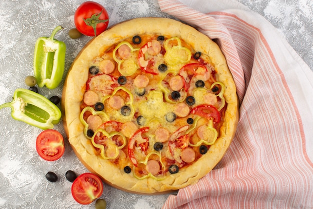 Top view tasty cheesy pizza with black olives sausages and red tomatoes on the grey background fast-food italian dough meal bake