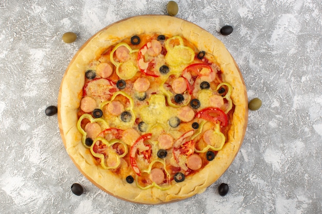 Top view tasty cheesy pizza with olives sausages and red tomatoes on the grey desk fast-food italian dough meal