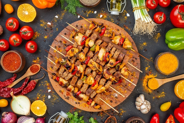 Top view tasty chicken skewers with spices on wooden board and other stuffs on table