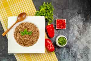 Free photo top view tasty cooked buckwheat with greens and bell-peppers on the light-grey table