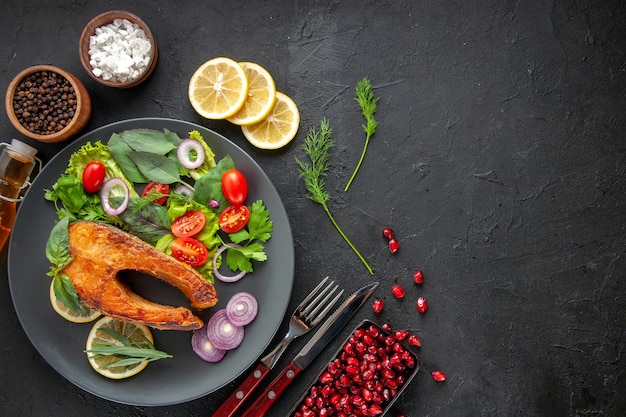 Free photo top view tasty cooked fish with fresh vegetables on dark table