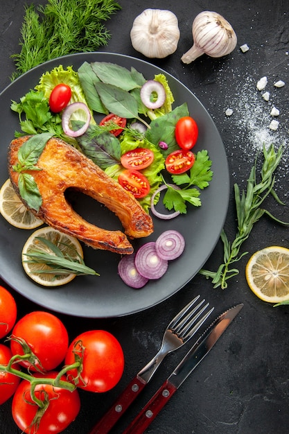 Free photo top view tasty cooked fish with fresh vegetables on the dark table