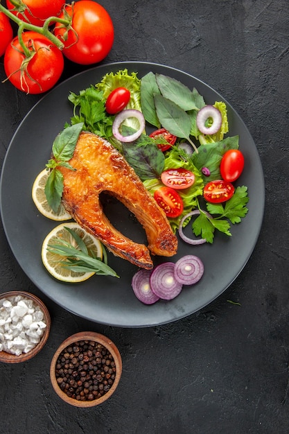 Free photo top view tasty cooked fish with fresh vegetables on dark table