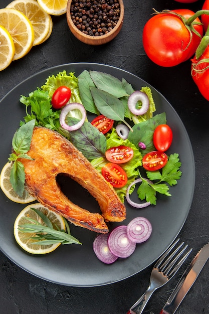 Free Photo top view tasty cooked fish with fresh vegetables and lemon slices on dark table