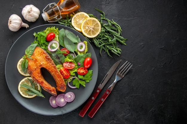 Free photo top view tasty cooked fish with fresh vegetables and seasonings on dark table color food meat dish photo